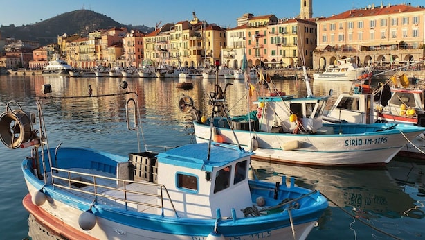 A harbor with boats docked, a prominent tower, and colorful buildings in the background. - Apartment in Imperia With Communal Pool (Imperia)