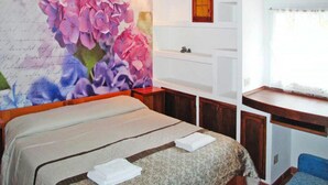 A bedroom with a bed, a desk, and a large floral mural on the wall. - Apartment in Imperia With Communal Pool (Imperia)