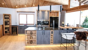 A modern kitchen with wooden cabinetry, a central island, and bar stools.