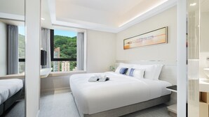 Een moderne hotelkamer met een groot bed, uitzicht op groen en een schilderij aan de muur.