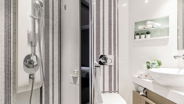 Een moderne badkamer met een douchecabine van glas, een toilet en een wastafel met een spiegel erboven.