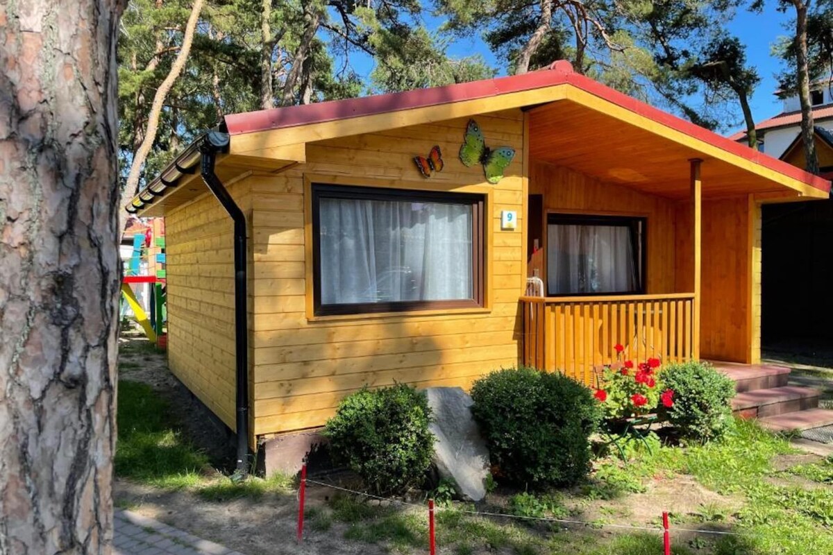 Eine kleine Holzhütte mit rotem Dach, einem Fenster und einer Schmetterlingsdekoration.