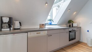 Eine moderne Küche mit Geschirrspüler, Backofen und Kaffeemaschine.