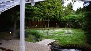 Un jardín con un estanque, una terraza de madera y un sendero de ladrillo.