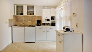 Cocina compacta con alacenas blancas, cafetera y microondas sobre una pequeña encimera.