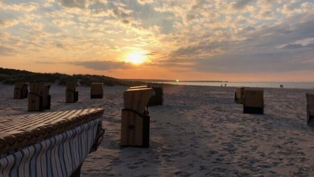 Une plage avec des chaises longues et une terrasse en bois.