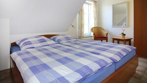 Une chambre avec une couvre-lit à carreaux, une chaise, une petite table et un miroir au mur.
