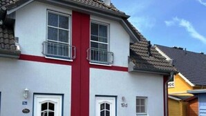 Une maison à deux étages, à la façade rouge et blanche, portant le numéro 19d, avec une porte d’entrée et des fenêtres.
