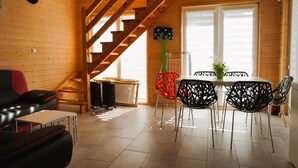 A wooden interior with a staircase, a dining area with chairs, a sofa, and a table. - Rewal Holiday Home Near Baltic Beach (Rewal)
