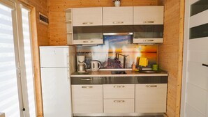 A kitchen with wooden walls, a refrigerator, a coffee maker, and a sink. - Rewal Holiday Home Near Baltic Beach (Rewal)