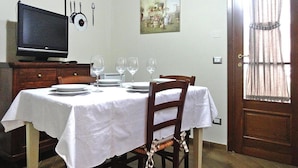 Ein Essbereich mit einem Tisch für vier Personen, einem Fernseher auf einer Holzkommode und einem Bild an der Wand.