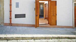 Un edificio a due piani con un balcone, una porta di legno e una piccola finestra.