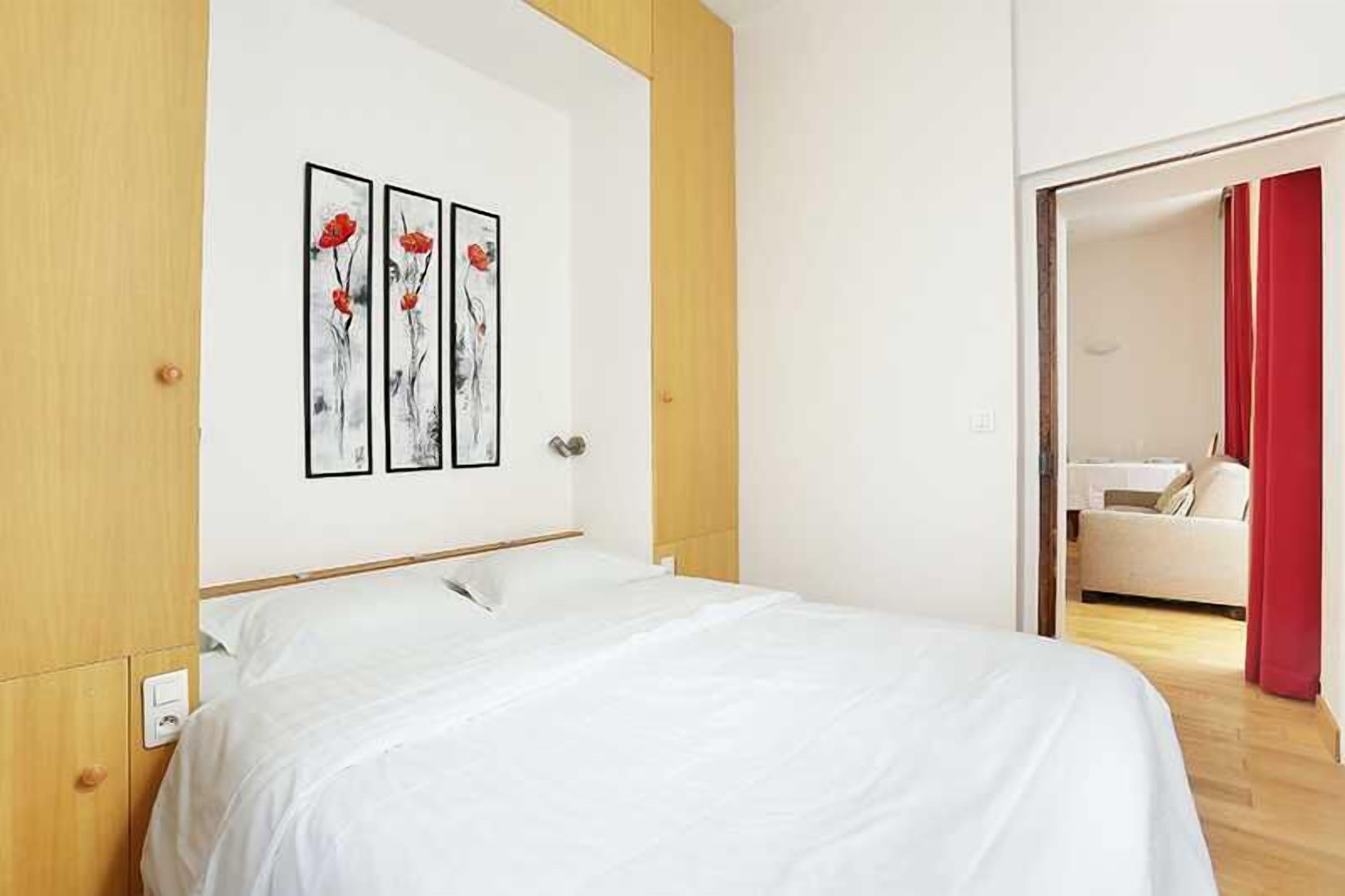 Una habitación de hotel con una cama, cabecero de madera y una pared con tres obras de arte enmarcadas.