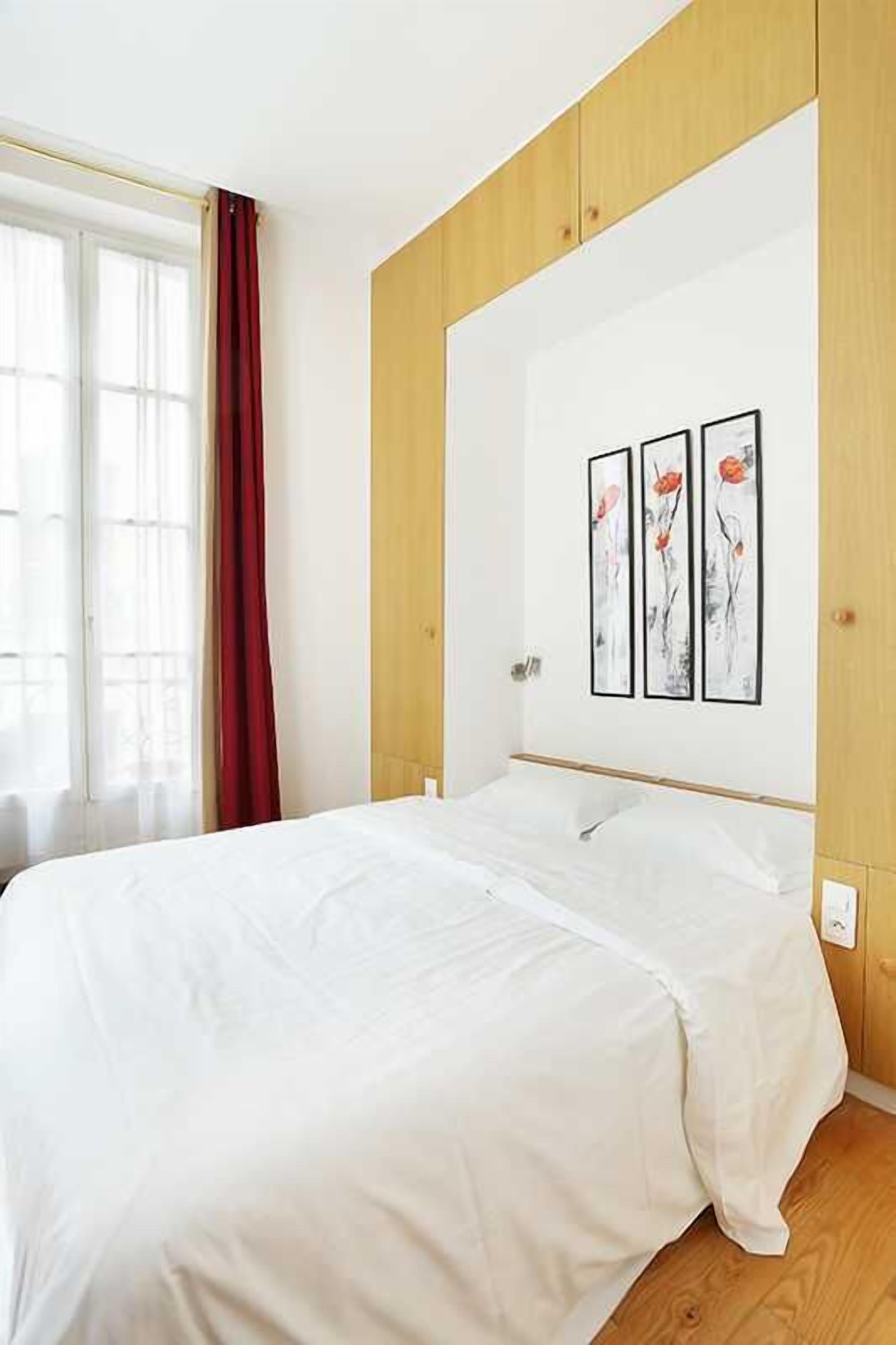 Un dormitorio con cama, paneles de madera y tres obras de arte enmarcadas en la pared.