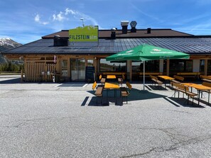 A building with a sign reading 'FILZSTEINalm' and outdoor seating with tables and chairs. - Apartment in Hochkrimml Near Ski Slopes (Krimml)