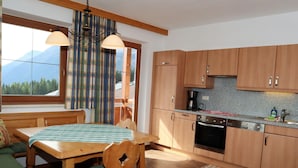 Une cuisine chaleureuse avec des meubles en bois, une table à manger et une vue sur les montagnes par la fenêtre.