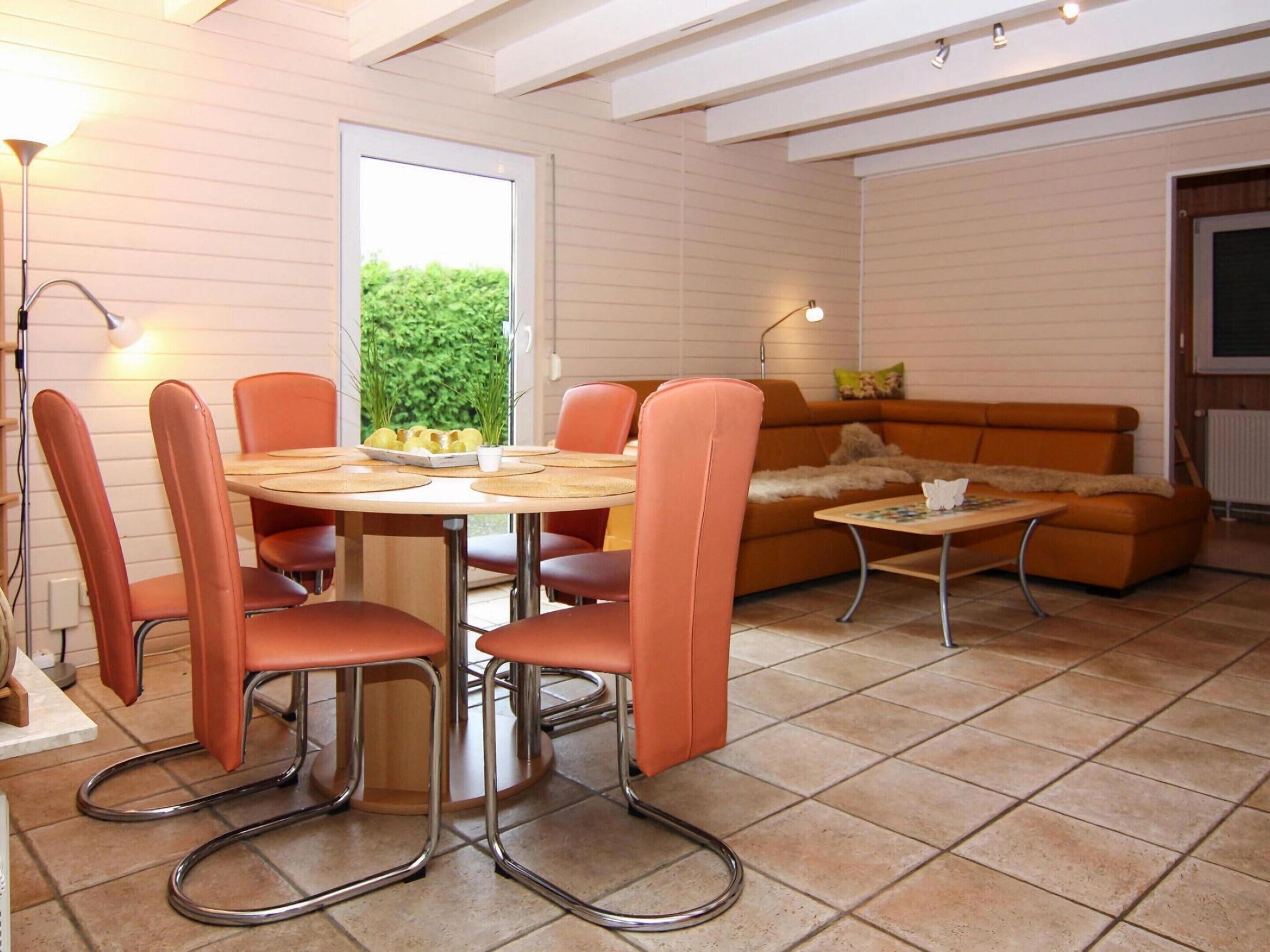 Un coin repas comprenant une table ronde et des chaises, un canapé et une petite table avec une lampe.