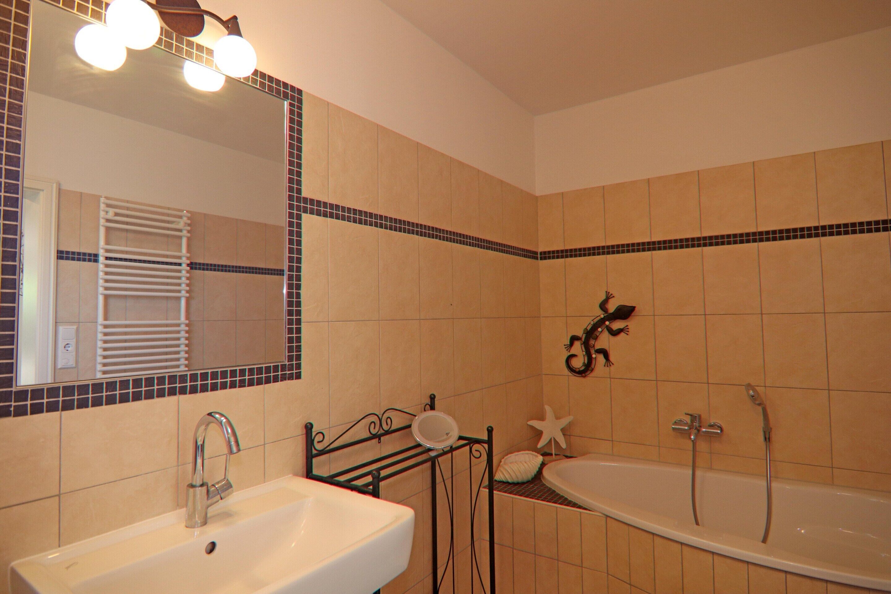 A bathroom with a sink, mirror, and bathtub.