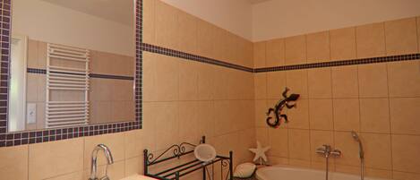 A bathroom with a sink, mirror, and bathtub.
