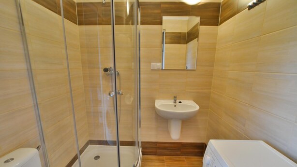 A bathroom with a glass-enclosed shower, a sink, a toilet, and a washing machine. - Comfortable Holiday Homes, Close to the sea (Ustronie Morskie)