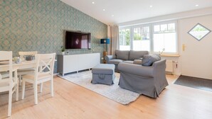 A living room with a TV, sofa, and a dining area with chairs and a table.