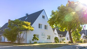 A white building with a thatched roof, a sign reading "Hotel", and a tree in front.