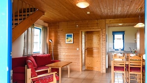 A wooden interior with a sofa, table, chairs, a staircase, and a kitchen area. - Ferienpark Harz in Hasselfelde (Oberharz am Brocken)