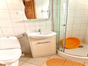A bathroom with a toilet, sink, and glass shower enclosure.