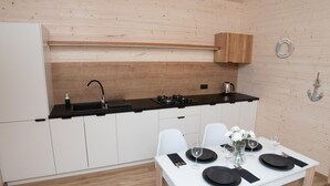 Een moderne keuken met witte kastjes, een zwart aanrecht en een houten plafond.