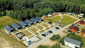 Luchtbeeld van een camping met meerdere huisjes, een parkeerplaats en een zwembad.