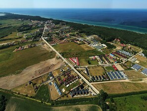 Vue aérienne d’une ville côtière, avec ses quartiers résidentiels, des panneaux solaires et une vue dégagée sur la mer.