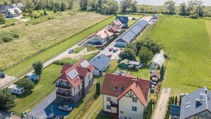An aerial view of a residential area with houses, a road, and a body of water in the background. - Apartment in Krynica Morska Near Vistula Lagoon (Krynica Morska)