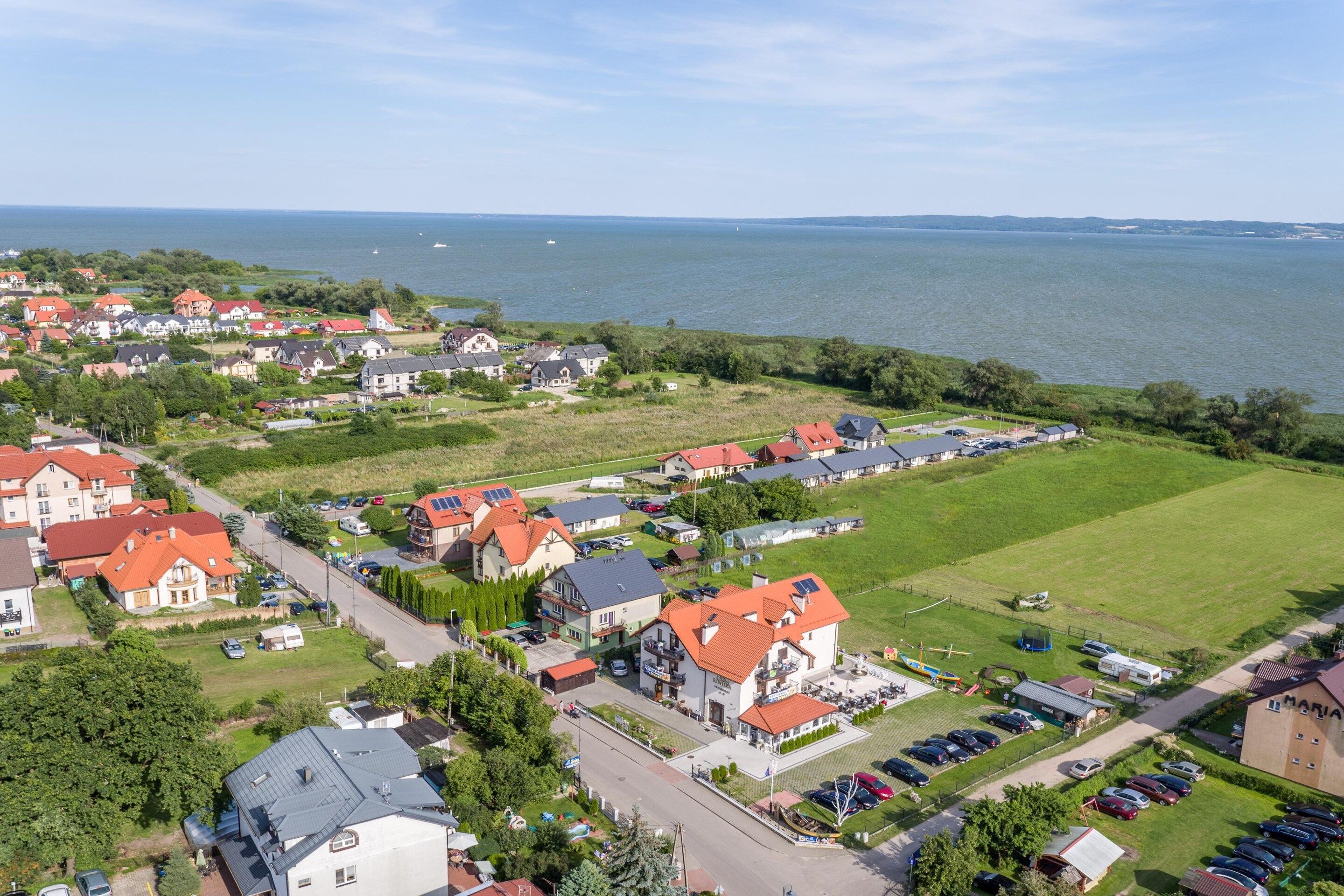 Une zone résidentielle côtière comprenant des maisons, un port de plaisance et une vaste étendue d’eau.