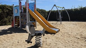 A playground with a slide, swings, and a climbing structure. - Apartment in Krynica Morska Near Vistula Lagoon (Krynica Morska)