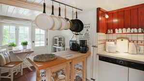 Une cuisine avec des ustensiles de cuisine suspendus, une machine à café et un lave-vaisselle.