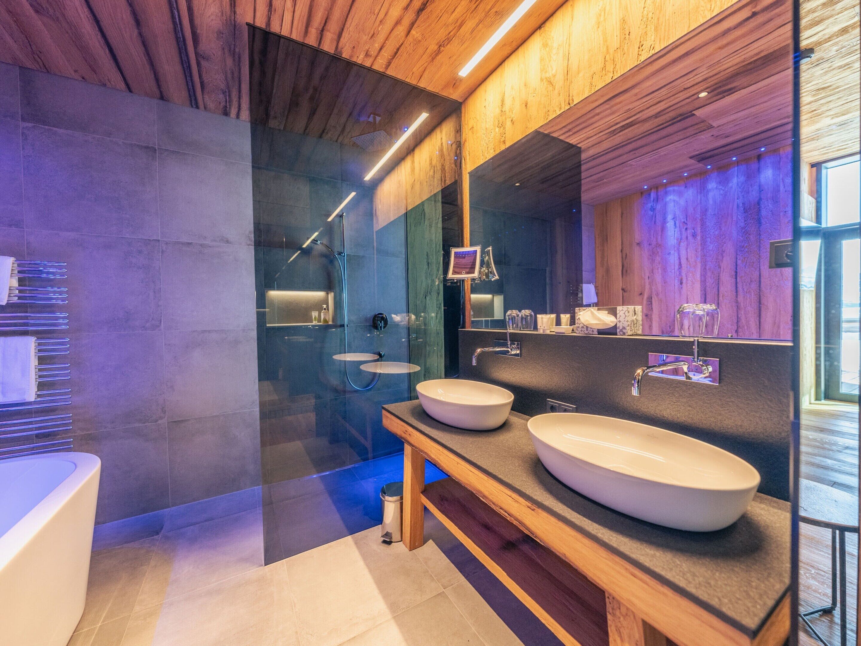 Un bagno moderno con due lavabi, una cabina doccia in vetro e un mobile bagno in legno.