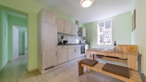 A modern kitchen with light wooden cabinets, a built-in oven, and a window with a view of buildings. - Ferienwohnung Schlossblick, Wernigerode (Wernigerode)