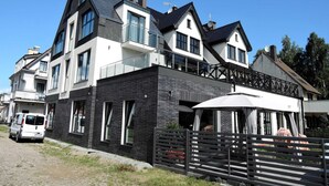 A modern two-story building with a mix of black and white exterior, large windows, and a balcony. - Apartment in Mrzezyno by Blue Flag Beach (Trzebiatow)