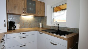 A modern kitchen with wooden cabinets, a black sink, and a coffee maker. - Apartment in Bramberg Near Ski Lift & Wildkogel (Bramberg am Wildkogel)
