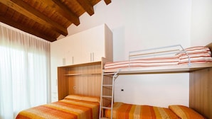 A dormitory room with two beds, a bunk bed, a ladder, and a window with curtains. - Apartment in Caorle With Heating (Caorle)