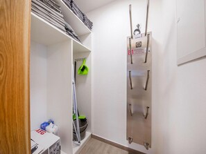 Compact bathroom with shelf, wall-mounted radiator, and storage area.