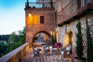 A stone patio with wicker furniture, an archway, and a view of the surrounding landscape. - Casabella With Garden (Monteleone d'Orvieto)