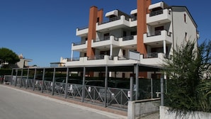A multi-story residential building with balconies, a covered parking area, and a gated entrance. - Residence Vecchio Faro in Cavallino-treporti-formerly TUI Ferienhaus (Cavallino-Treporti)