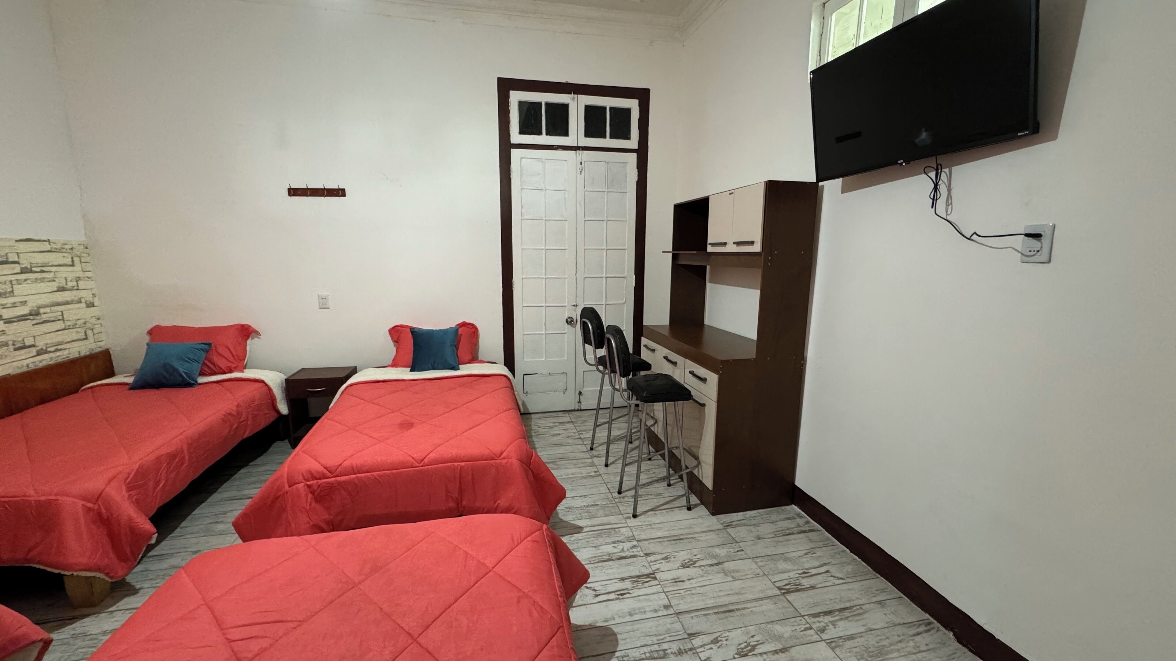 Una habitación con dos camas, televisión, escritorio y una silla.