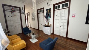 Un amplio salón con una mesa de centro de cristal, dos sofás y una araña.