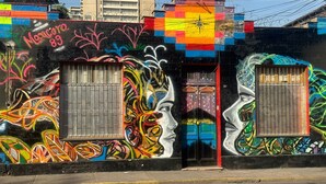 Un edificio con arte callejero de colores, incluyendo dos grandes ventanas y una puerta roja.
