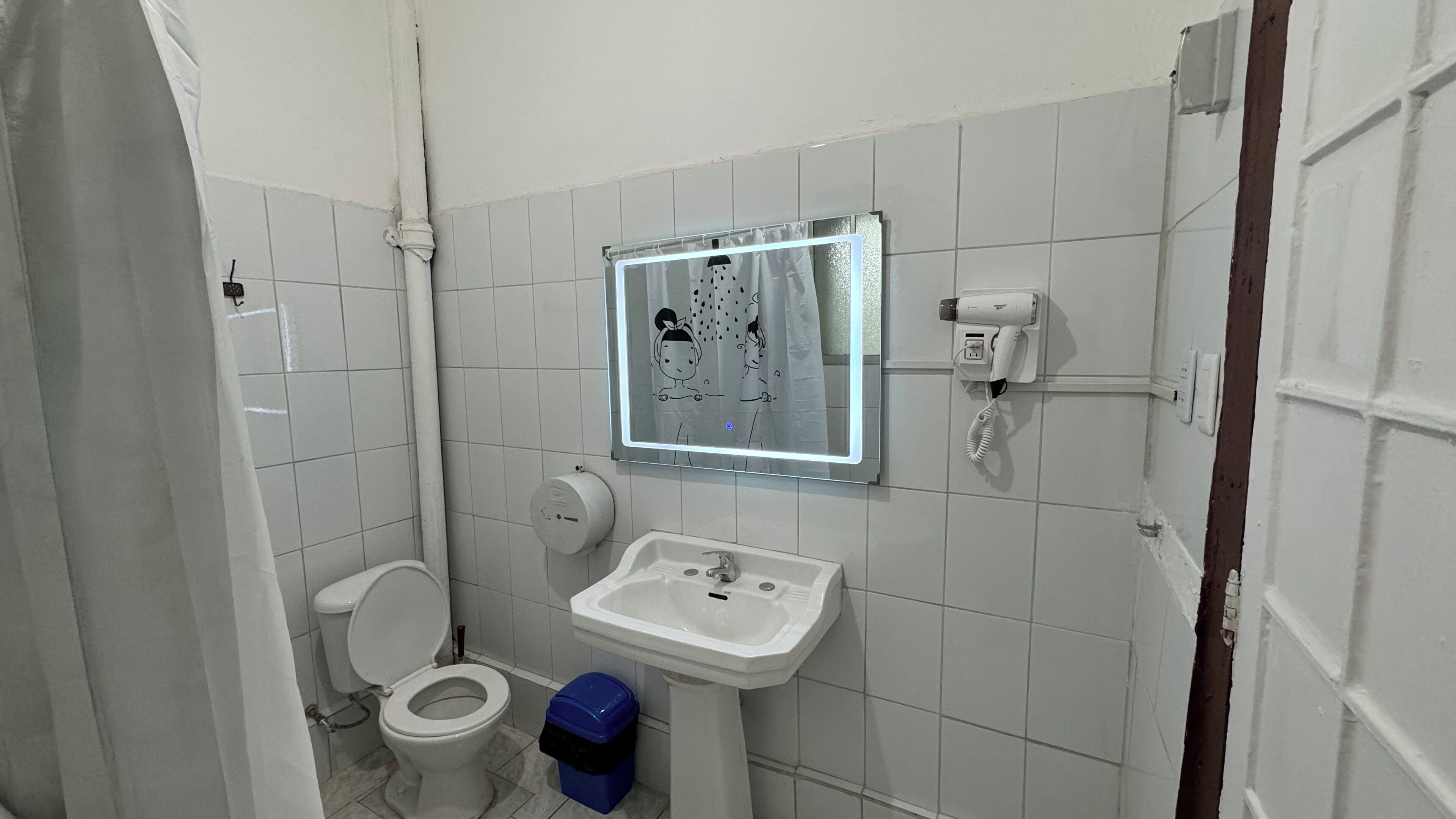 Baño pequeño y sencillo con inodoro, lavamanos y espejo con marco decorativo.