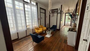 Una habitación amplia con suelo de madera, una mesa de centro de vidrio y dos sillones.
