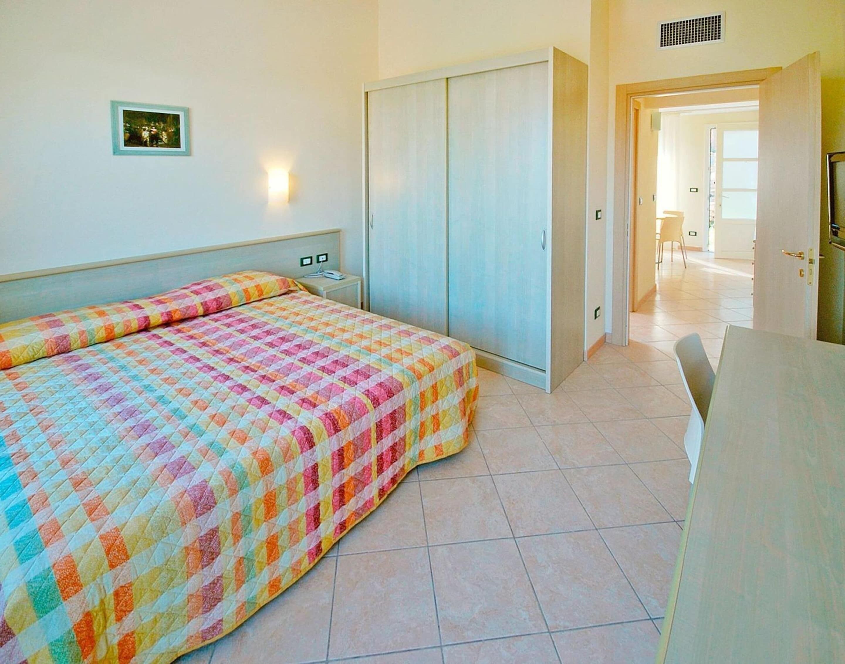 A bedroom with a bed, a wardrobe, a nightstand, and a picture on the wall.