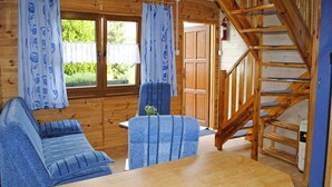 A wooden cabin interior with a sofa, a table, and a staircase. - Two-story Wooden Houses Close to the Beach (Mielno)